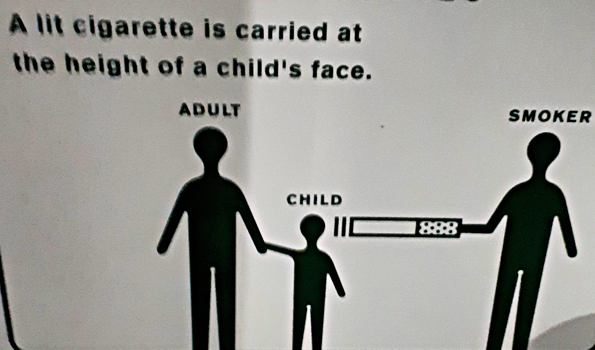 A lit cigarette is carried at the height of a child's face